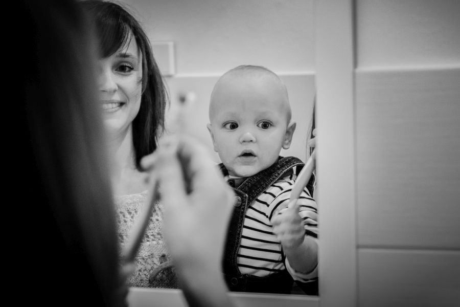 Das Spiegelbild meiner Mutter und ihres Kleinkindes beim Zähneputzen. Schwarz-Weiß.