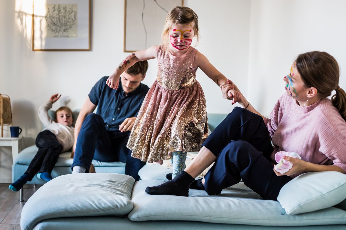 Eine vierköpfige Familie tobt gemeinsam auf dem Sofa.