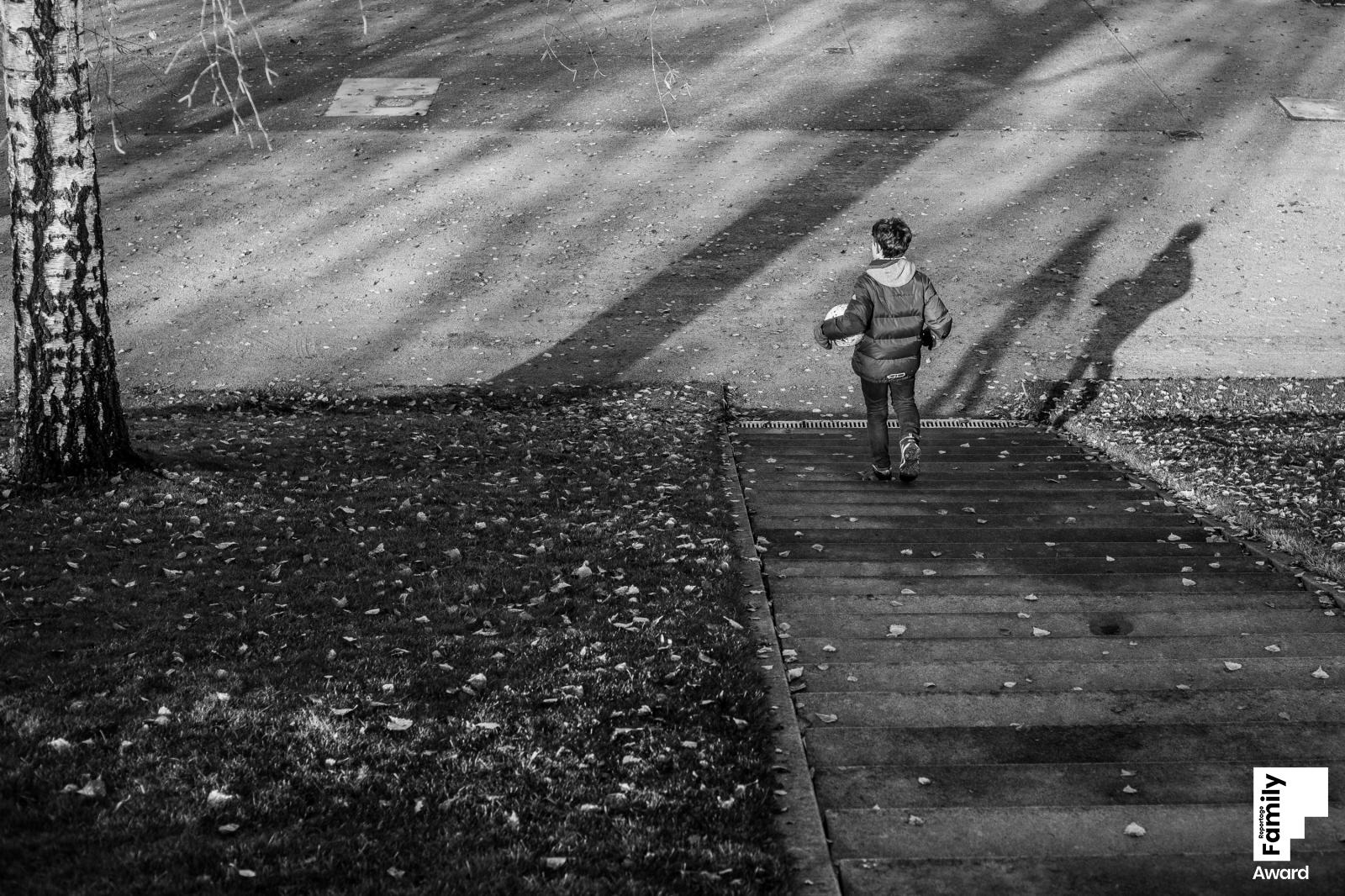 Ein Junge mit einem Fußball unter dem Arm geht eine Treppe im Volkspark hinunter. Seitlich vor ihm sind sein Schatten und der eines zweiten Kindes zu sehen.