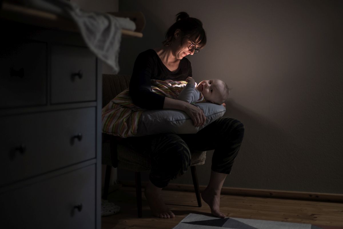Eine Mutter stillt bei atmosphärischem Licht ihr Kind.
